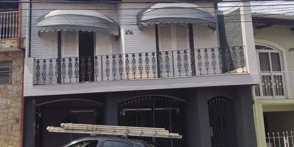 a frente da casa. dus sacadas com toldo e grade de proteção